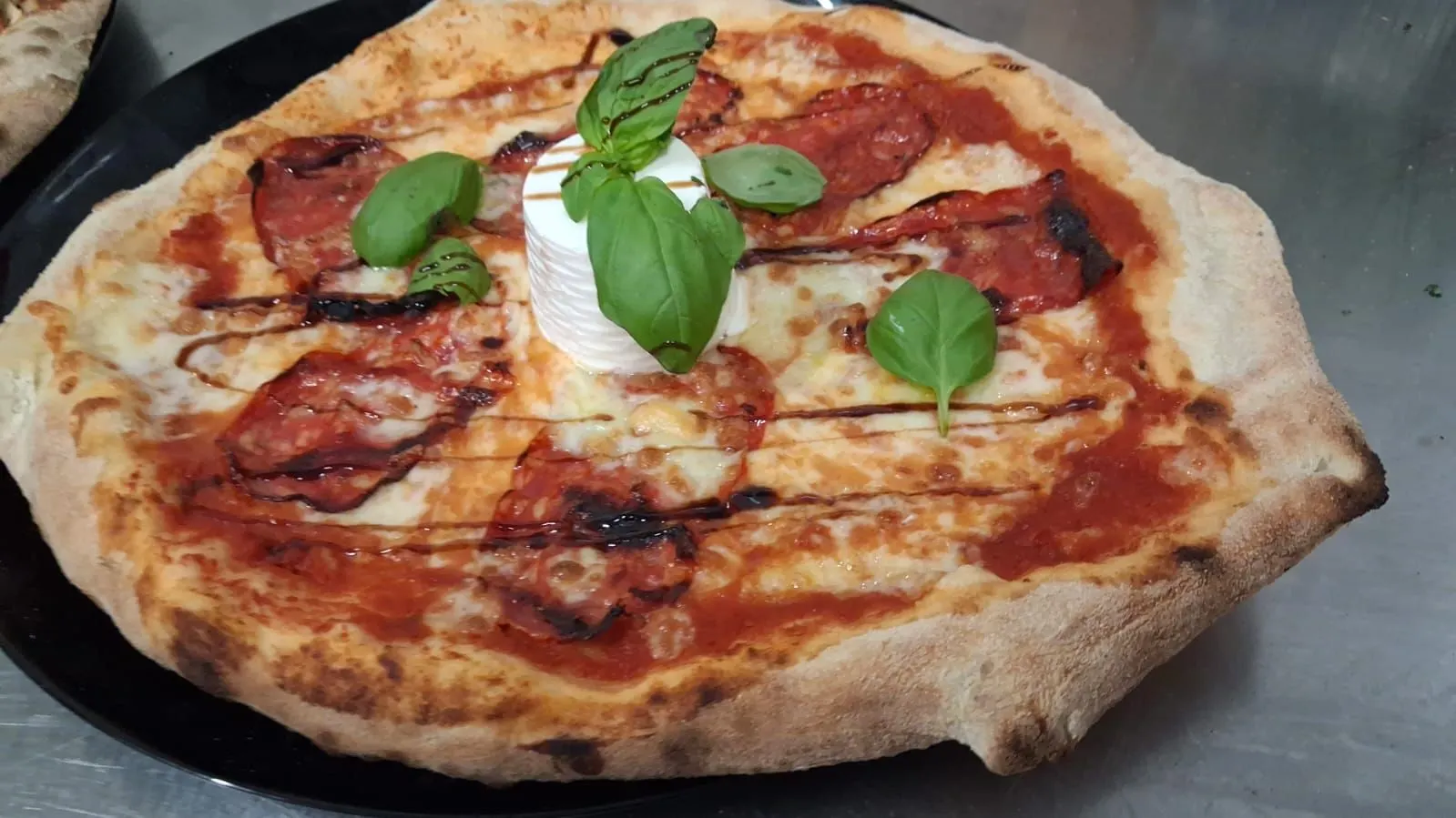 Steinofenpizza mit cremiger Burrata, frischem Basilikum und knusprigem Rand